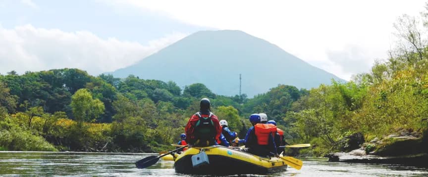 羊蹄山を望む川でラフティングを楽しむ人々